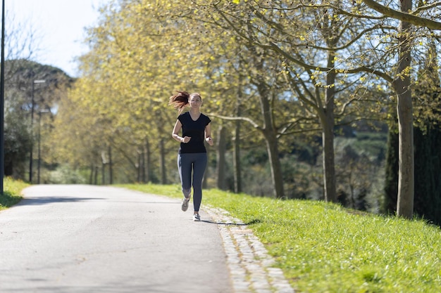 Adult fitness woman jogging on the track in the park