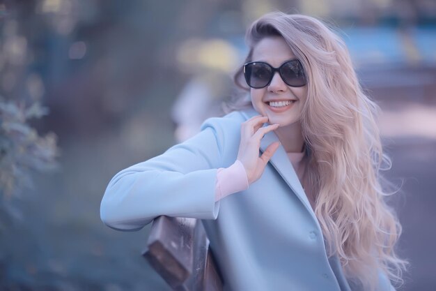 adult girl sitting on a bench in the park / beautiful model woman resting on a bench, cheerful happy girl