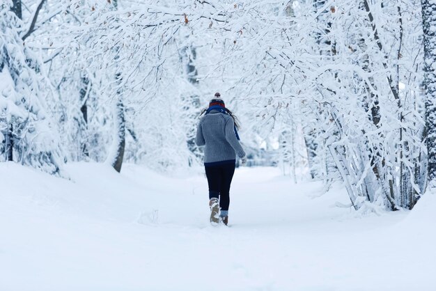 冬の雪の森でスウェーターを着た大人の女の子