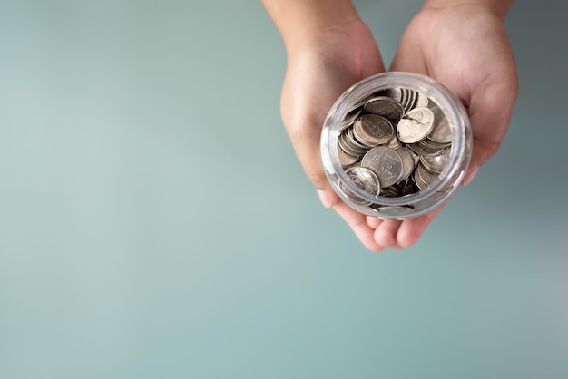 Adult hands holding a jar with coins in savings and donation concept