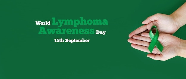 Adult hands holds green ribbon on green background World lymphoma awareness day September 15