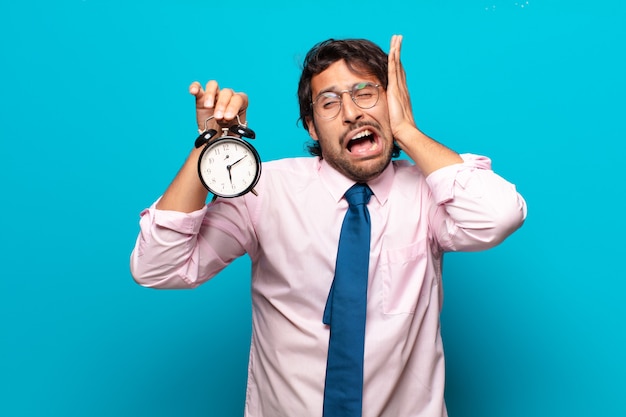 Adult handsome indian businessman with an alarm clock