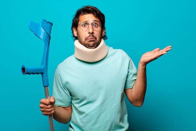 Adult handsome indian man who has suffered an accident.  crutch and collar concept