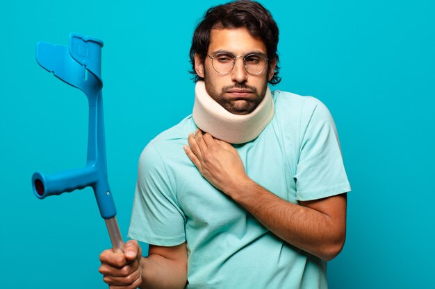 Adult handsome indian man who has suffered an accident.  crutch and collar concept