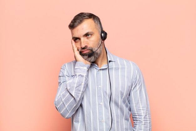 Adult handsome man feeling bored, frustrated and sleepy after a tiresome, dull and tedious task, holding face with hand