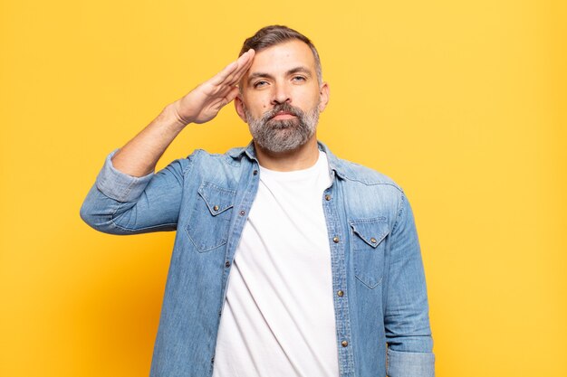 adult handsome man greeting with a military salute in an act of honor and patriotism, showing respect
