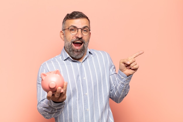 Adult handsome man laughing, looking happy, positive and surprised, realizing a great idea pointing to lateral copy space