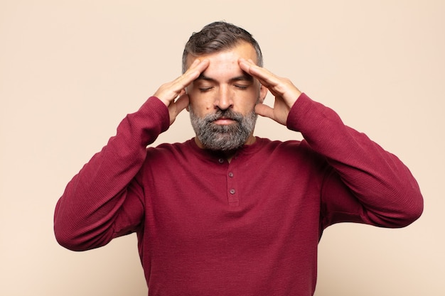 Adult handsome man looking concentrated, thoughtful and inspired, brainstorming and imagining with hands on forehead