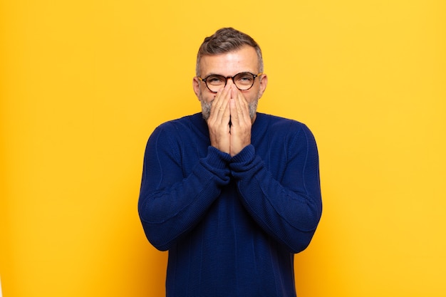 Adult handsome man looking happy, cheerful, lucky and surprised covering mouth with both hands