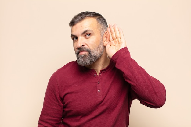 Adult handsome man smiling, looking curiously to the side, trying to listen to gossip or overhearing a secret