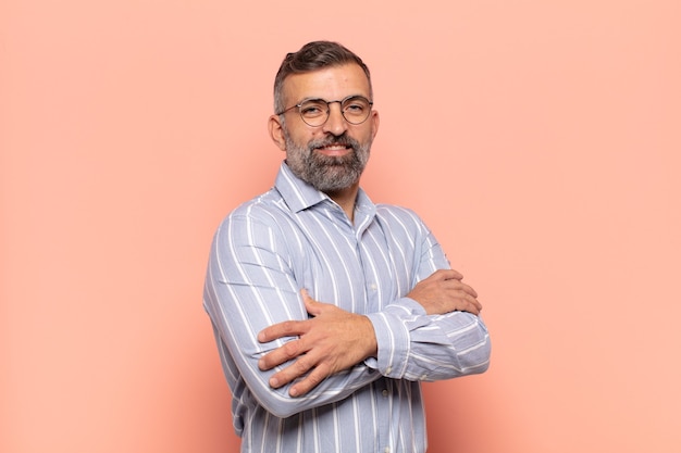 Adult handsome man smiling with crossed arms and a happy, confident, satisfied expression, lateral view