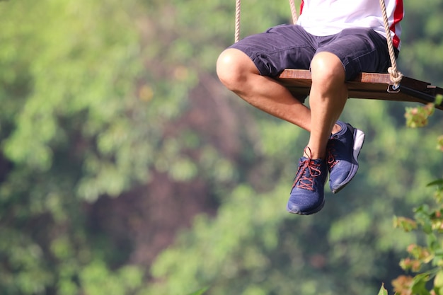 Photo adult legs sitting on swing  loneliness playing in the park playful and happy the outside background