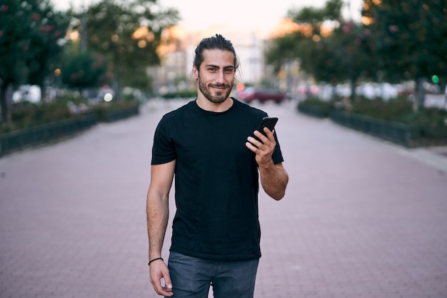 Adult long haired man walking on the street whilst having a business phone call