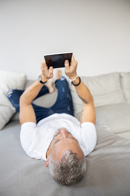 Adulto sdraiato su un divano con un tablet
