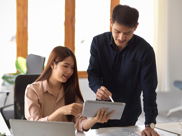 An adult male boss training and giving a work feedback to his female assistant in the office