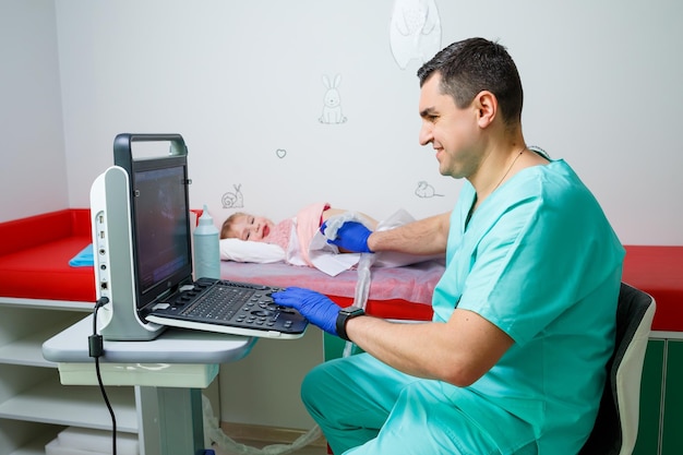 An adult male doctor makes an ultrasound scan to a little girl. Medical examination of the child.
