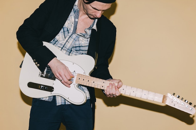 Adult male guitarist assiduously playing guitar