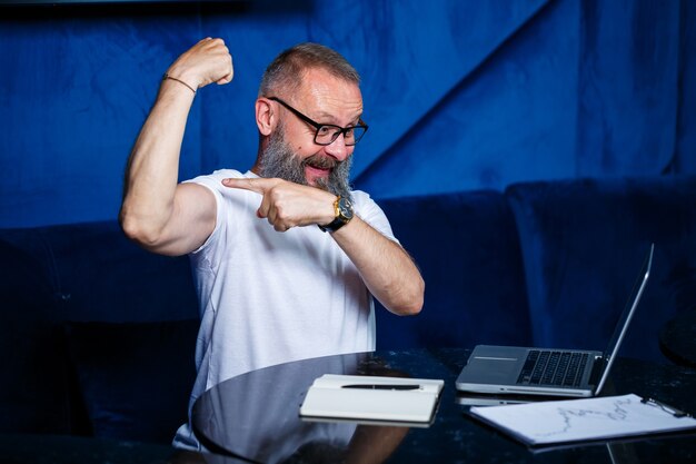 Foto mentore maschio adulto, direttore, uomo d'affari con gli occhiali e un vestito che studia documenti mentre è seduto al tavolo. concetto di giornata lavorativa