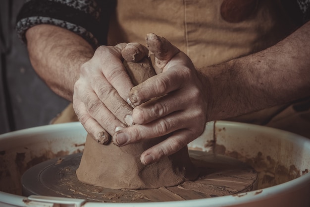 粘土を粉砕する成人男性の陶工マスター