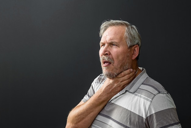 Adult male with an attack of suffocation or sore throat on a black background