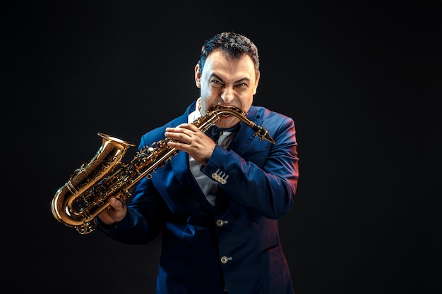 Adult man biting saxophone