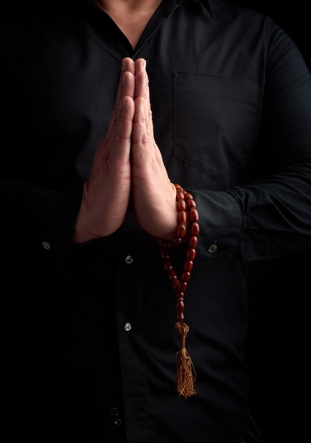 Adult man in a black shirt folded his arms in front of his chest in a prayer pose