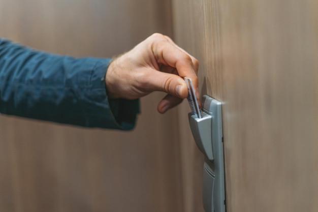 Adult man in blue jacket uses key card in the hotel room