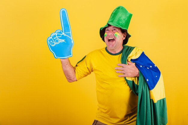 Adult man brazil soccer fan wearing flag with foam finger partying