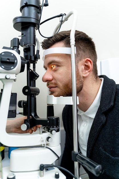 Adult man checks eyesight with binocular slit-lamp. Checking retina of a male eye close-up. Modern ophthalmology clinic.