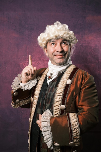 Photo adult man in classical renaissance clothing pointing up with finger showing something.