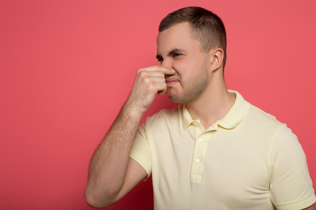 adult man covering nose with hand on pink