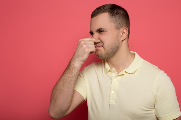 Photo adult man covering nose with hand on pink