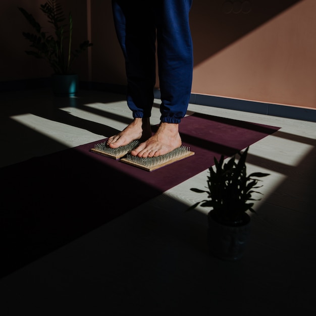 an adult man does yoga exercises. feet stand on a Board with sharp nails, close-up.