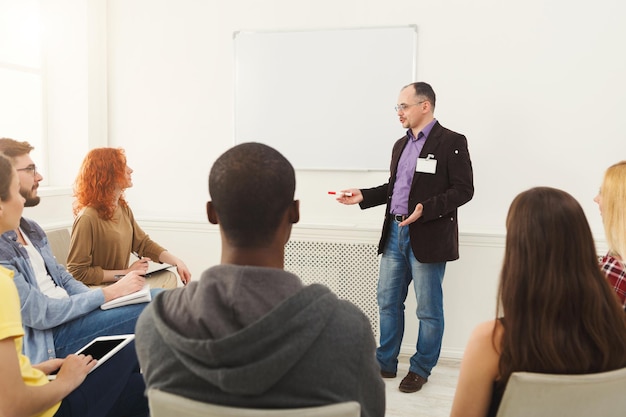 Uomo adulto che fa presentazione in ufficio, copia spazio. riunione d'affari di avvio, condivisione di nuove idee con i partner, concetto di lavoro di squadra