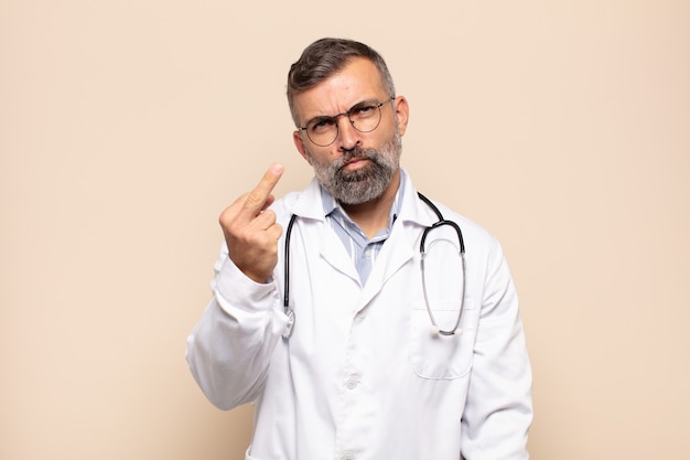 Adult man feeling angry, annoyed, rebellious and aggressive, flipping the middle finger, fighting back