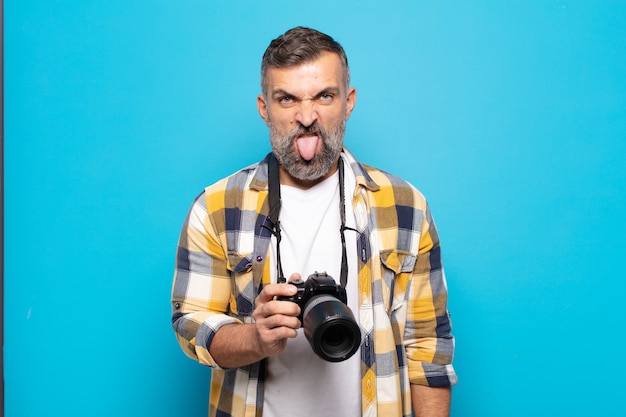 Adult man feeling disgusted and irritated, sticking tongue out, disliking something nasty and yucky