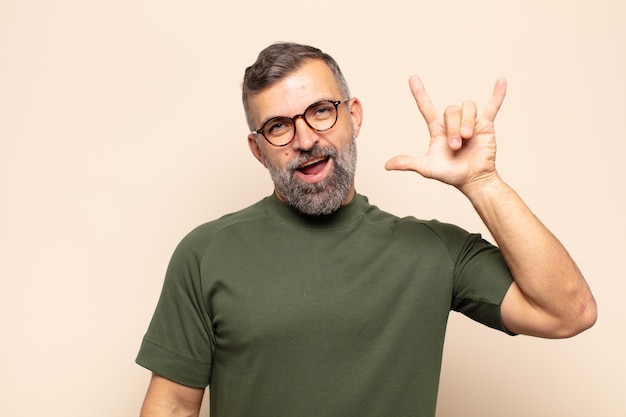 Adult man feeling happy, fun, confident, positive and rebellious, making rock or heavy metal sign with hand