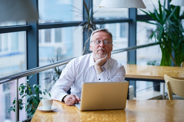 Adult man in glasses manager businessman worked successfully and at the end of the day drinks coffee without a jacket