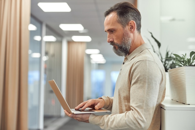 L'uomo adulto sta lavorando in un ufficio moderno