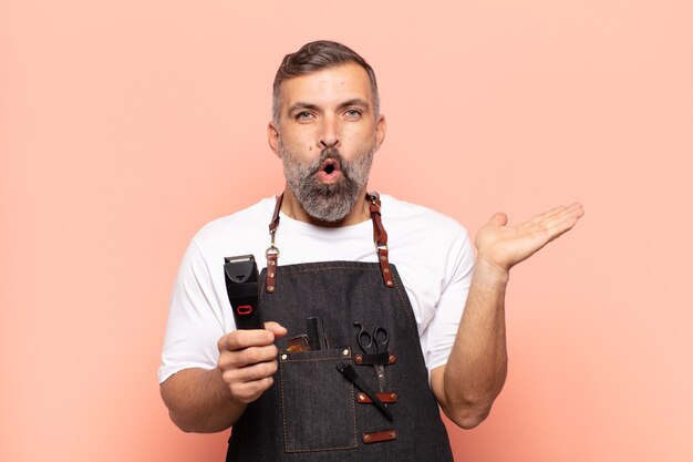 Adult man looking surprised and shocked, with jaw dropped holding an object with an open hand on the side