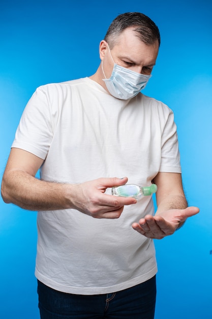 Adult man in mask protecting his hands with sanitizer