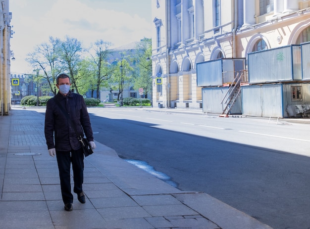 An adult man in a medical mask walks down an empty street