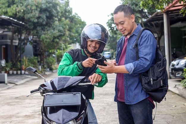 商用バイクタクシーの運転手にスマートフォンで注文する成人男性