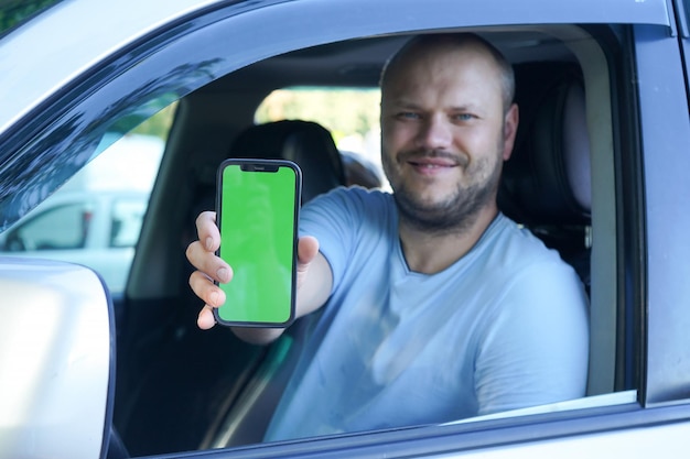 Adult Man show blank smartphone screen from car Foucs on mobile concept of online booking servive app advertising for travel service and promotions