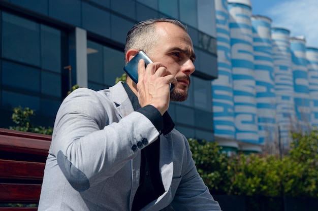 adult man sitting outdoors serious attentive on phone call copy space