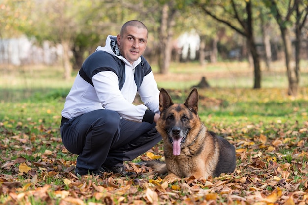 Adult Man Sitting Outdoors With His German Shepherd