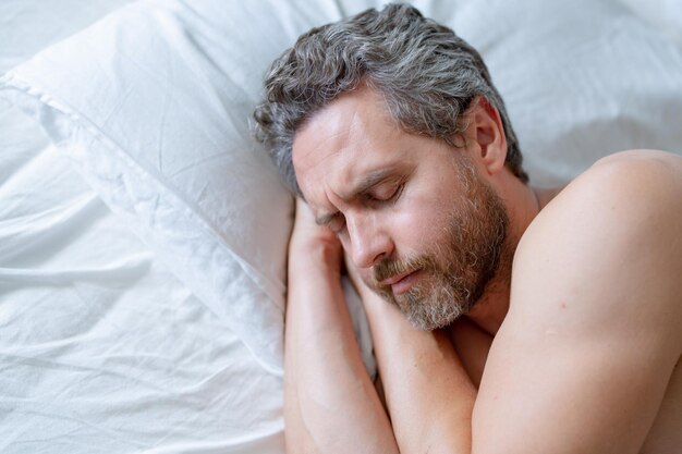Foto uomo adulto dorme in un letto bianco uomo bello senza camicia che dorme nel letto in camera da letto uomo maturo ispanico