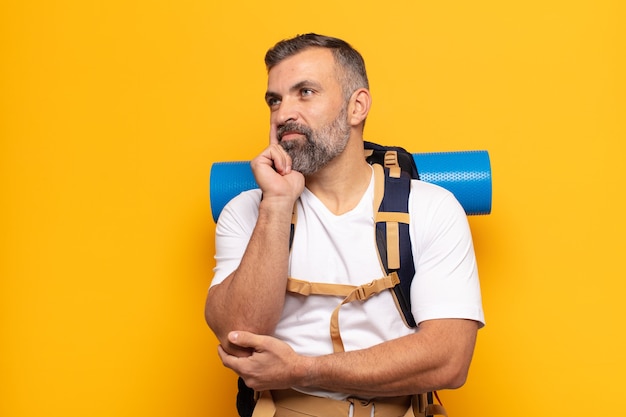 Adult man smiling happily and daydreaming or doubting, looking to the side