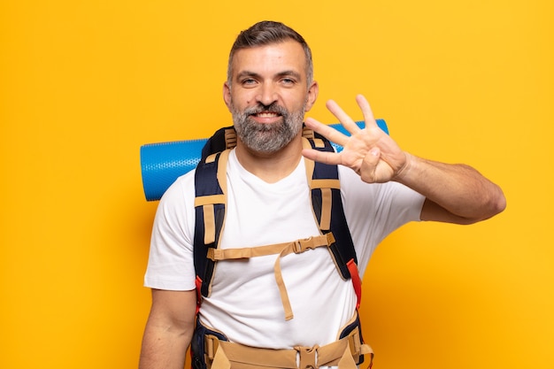 Adult man smiling and looking friendly, showing number four or fourth with hand forward, counting down