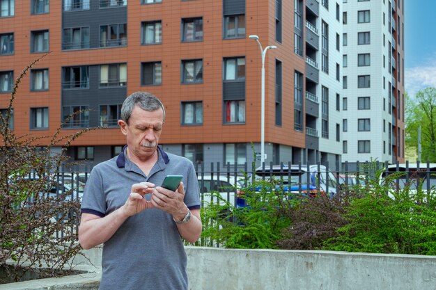 Foto un uomo adulto si alza e scrive un messaggio su uno smartphone